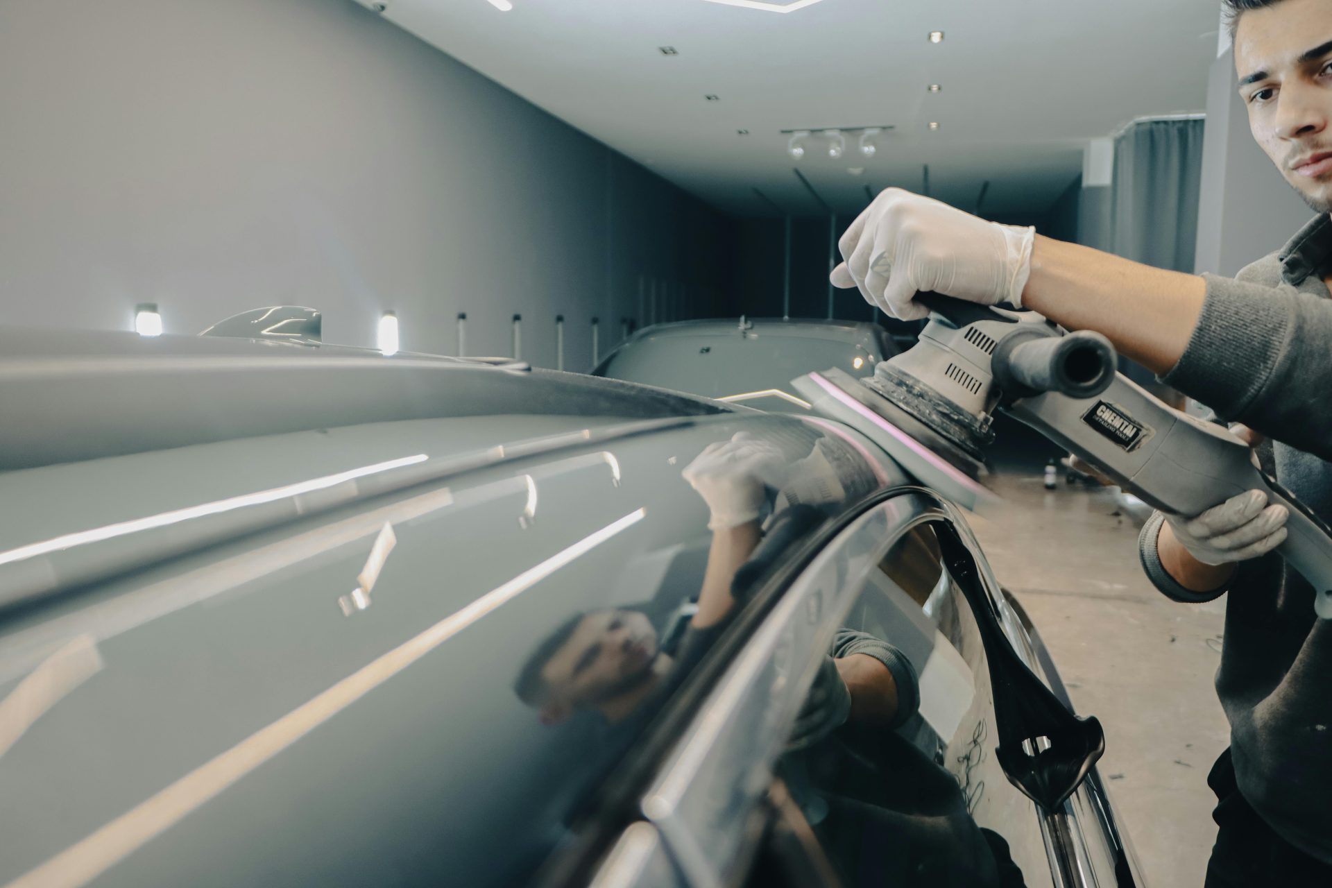 Man meticulously washing car in auto workshop, focusing on detail and quality.